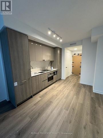 Vaughan (Vaughan Corporate Centre) condo for rent - A modern kitchen with wooden floors and cabinets.