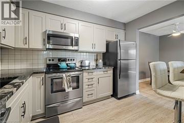 Thorold condo for rent - A kitchen with a stove top oven, microwave, refrigerator, and cabinets.