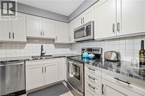 Thorold condo for rent - A kitchen with white cabinets and a black counter top.