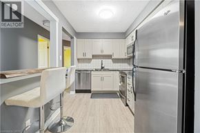 Thorold condo for rent - A modern kitchen with a stainless steel refrigerator and white bar stools.