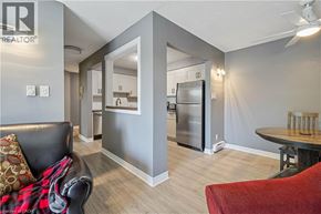 Thorold condo for rent - A living room with a couch, a chair, and a kitchen area in the background.
