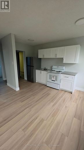 Hamilton (Mcquesten) multi-family for rent - A kitchen with white cabinets and a white stove top oven.