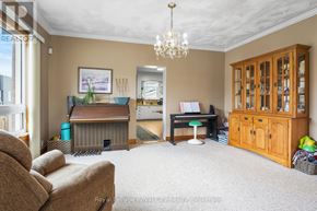 Guelph (Junction/Onward Willow) apartment for rent - A living room with a brown sofa, a wooden desk, and a chandelier.