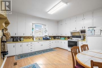Guelph (Junction/Onward Willow) apartment for rent - A kitchen with white cabinets and a table with chairs.