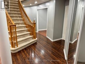 Oshawa (Pinecrest) apartment for rent - A staircase with wooden handrails and a beige carpeted runner leads to a landing with a white door.