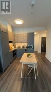 Markham (Commerce Valley) condo for rent - A modern kitchen with a table and chairs in the middle.