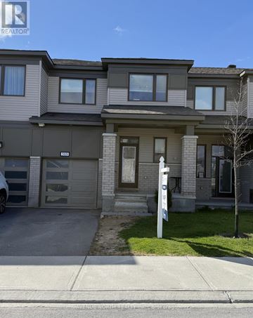 Ottawa townhouse for rent - A realtor photo of a grey house with a white sign in front.