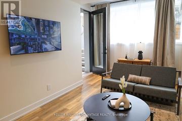 Toronto (Rockcliffe-Smythe) multi-family for rent - A living room with a grey couch and a painting on the wall.