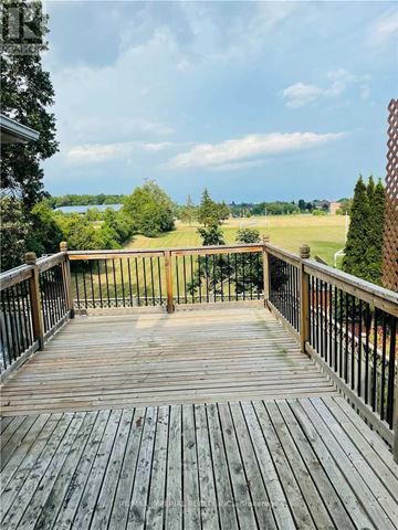 Mississauga (Hurontario) apartment for rent - A wooden deck with a metal railing overlooks a grassy field.