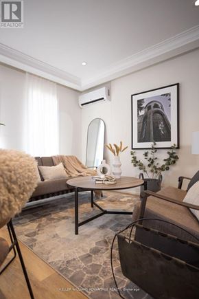 Toronto (Rockcliffe-Smythe) multi-family for rent - A living room with a brown couch, a round table, and a framed picture on the wall.