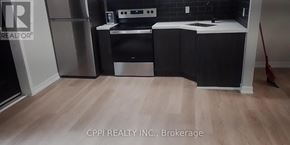 Peterborough (Town Ward 3) condo for rent - A kitchen with black cabinets and a wooden floor.