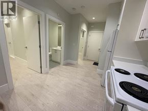 Vancouver apartment for rent - A white stove is in a room with white walls and a white floor.