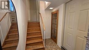 Toronto (Downsview-Roding-Cfb) apartment for rent - A hallway with a wooden staircase and a white door.