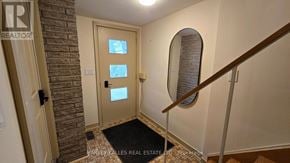 Toronto (Downsview-Roding-Cfb) apartment for rent - A hallway with a brick wall and a wooden staircase.