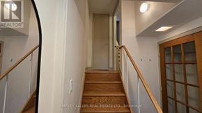 Toronto (Downsview-Roding-Cfb) apartment for rent - A hallway with a wooden staircase and white walls.