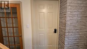 Toronto (Downsview-Roding-Cfb) apartment for rent - A white door with a black handle is in a room with a brick wall.