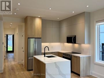 Toronto (Clanton Park) multi-family for rent - A modern kitchen with wooden cabinets and a white island.