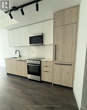 Toronto (Centennial Scarborough) condo for rent - A modern kitchen with wooden cabinets and a stainless steel oven.