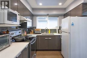 Richmond apartment for rent - A modern kitchen with a white refrigerator, stainless steel appliances, and a window.