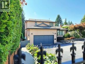 North Vancouver apartment for rent - A house with a garage is surrounded by a fence and greenery.