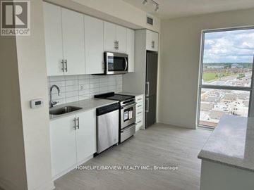 Oakville (Go Glenorchy) condo for rent - A kitchen with white cabinets and a microwave above the stove.