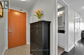 Ottawa condo for rent - A brown door is on the left of a black cabinet with a vase of flowers on top.