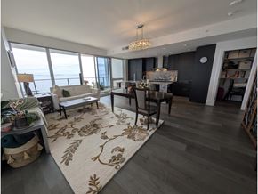 White Rock apartment for rent - A living room with a rug on the floor and a dining table with chairs.