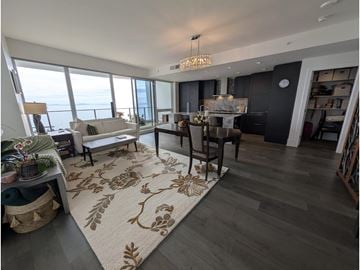 White Rock apartment for rent - A living room with a rug on the floor and a dining table with chairs.
