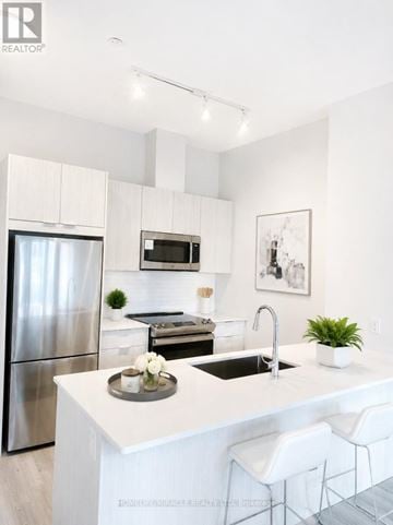 Mississauga (City Centre) condo for rent - A modern kitchen with white cabinets and a stainless steel refrigerator.