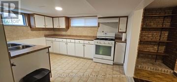 Toronto (Rustic) apartment for rent - A kitchen with white cabinets and a brick wall.