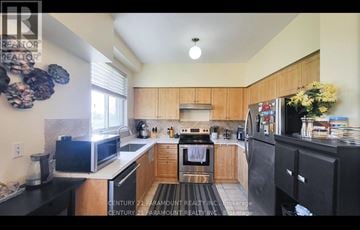 Mississauga (Meadowvale Village) townhouse for rent - A kitchen with wooden cabinets and black appliances.