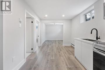 Welland (Welland Downtown) apartment for rent - A modern kitchen with white cabinets and a wooden floor.
