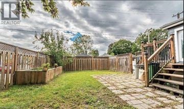 Hamilton apartment for rent - A backyard with a wooden fence and a staircase leading to a deck.