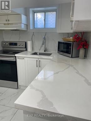 Toronto (Dorset Park) apartment for rent - A kitchen with white cabinets and a marble countertop.