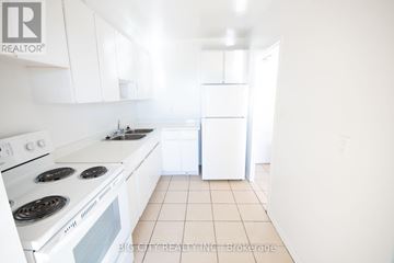 Toronto (Playter Estates-Danforth) condo for rent - A white kitchen with a stove top oven and a refrigerator.