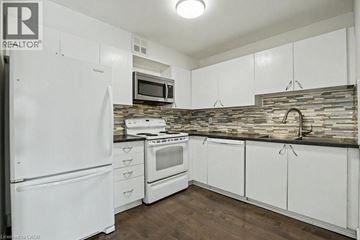 Kitchener condo for rent - A kitchen with white cabinets and a stone backsplash.