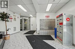 Kitchener condo for rent - A white tiled hallway with a mailbox and a tree.