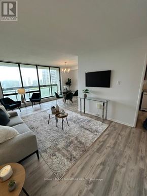 Toronto (Don Valley Village) condo for rent - A living room with a grey sofa, a coffee table, and a flat screen TV mounted on the wall.