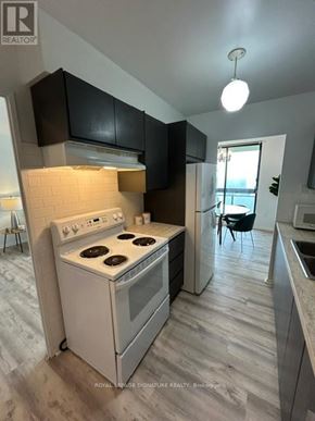 Toronto (Don Valley Village) condo for rent - A kitchen with a white stove and black cabinets.