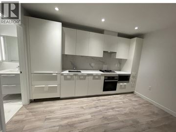 Burnaby apartment for rent - A modern kitchen with white cabinets and a wooden floor.