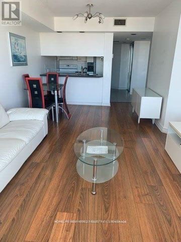 Toronto (Bay Street Corridor) condo for rent - A living room with a glass coffee table and white furniture.