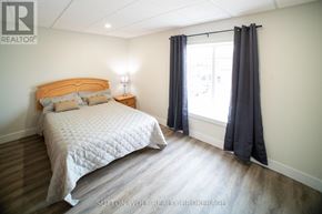 Strathroy-Caradoc (Nw) multi-family for rent - A bedroom with a bed, nightstand, and window.