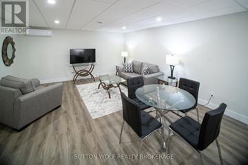 Strathroy-Caradoc (Nw) multi-family for rent - A modern living room with a glass table and black chairs.