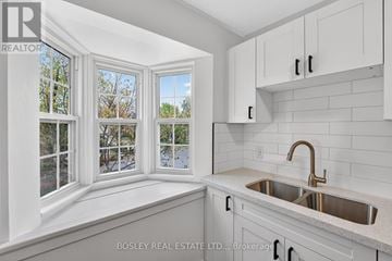 Niagara-On-The-Lake (Town) apartment for rent - A kitchen with white cabinets and a window overlooking trees.