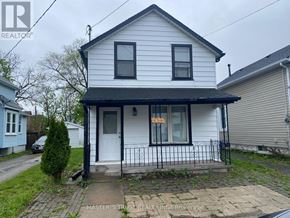 Niagara Falls (Downtown) apartment for rent - A white house with a black roof and a sign that says "For Sale".