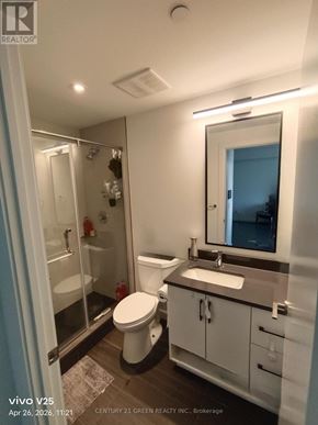 Kitchener condo for rent - A white toilet is in a bathroom with a sink and mirror.