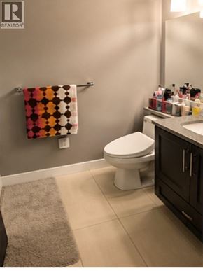 Coquitlam apartment for rent - A bathroom with a toilet, a towel rack with a towel, and a counter with bottles.