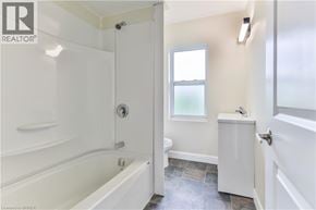 Brantford apartment for rent - A white bathroom with a tub, toilet, and sink.