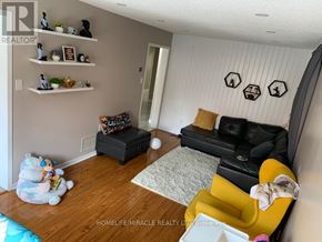Brampton (Fletcher's Creek South) apartment for rent - A living room with a black couch, a yellow chair, and a white wall with black decorations.