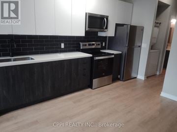 Peterborough (Town Ward 3) condo for rent - A kitchen with a black counter top and a refrigerator.
